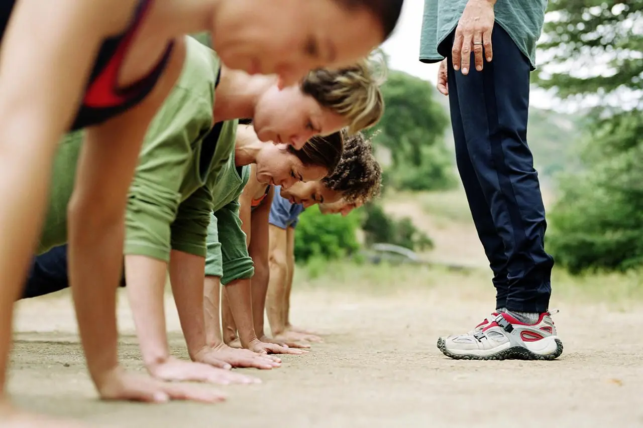 Four people do push-ups outdoors on dirt as one person observes, illustrating Modern Finance Function collaboration.