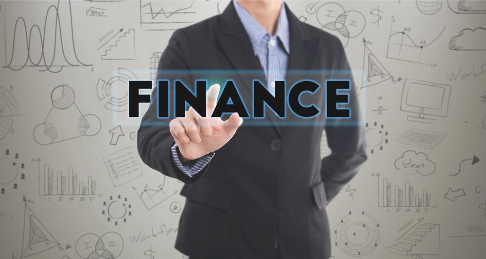 Business professional points to “FINANCE” on transparent screen with finance charts, showing Finance Business Partnering.